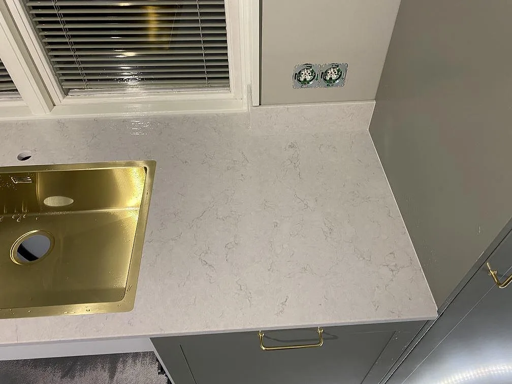 Bänkskiva i polerad Silestone Snowy Ibiza komposit med Stala Lagom-71 diskho och blandarhål vid fönster i Växjö.