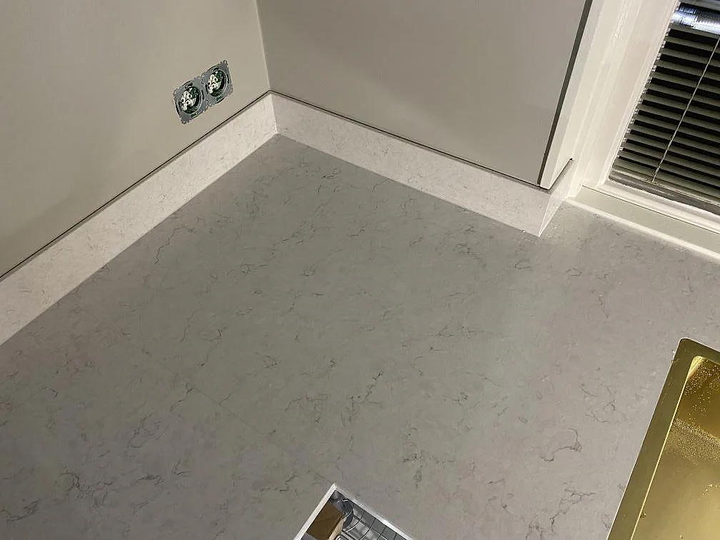 Hörnparti med polerad Silestone Snowy Ibiza bänkskiva och låg stänkskiva av komposit i ett kök i Växjö.