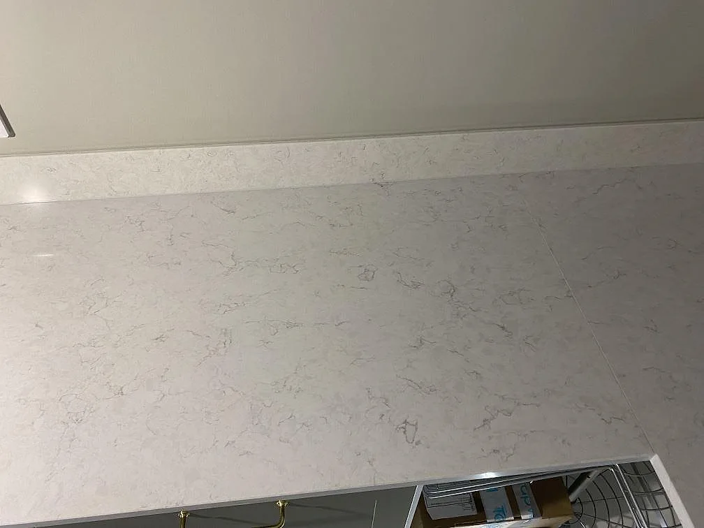 Rak bänkyta i polerad Silestone Snowy Ibiza komposit med låg stänkskiva längs väggen i Växjö.