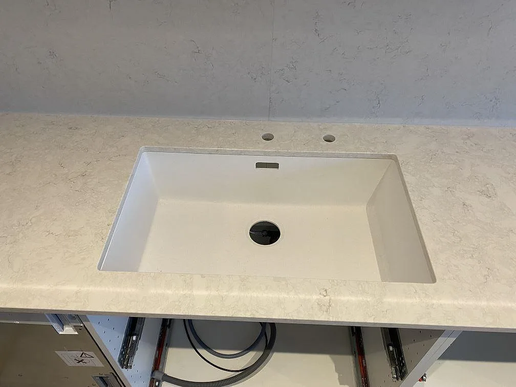 Diskbänksyta i polerad Silestone Snowy Ibiza med vit ho och kranhål, fotograferad under montering i ett kök i Vallberga.