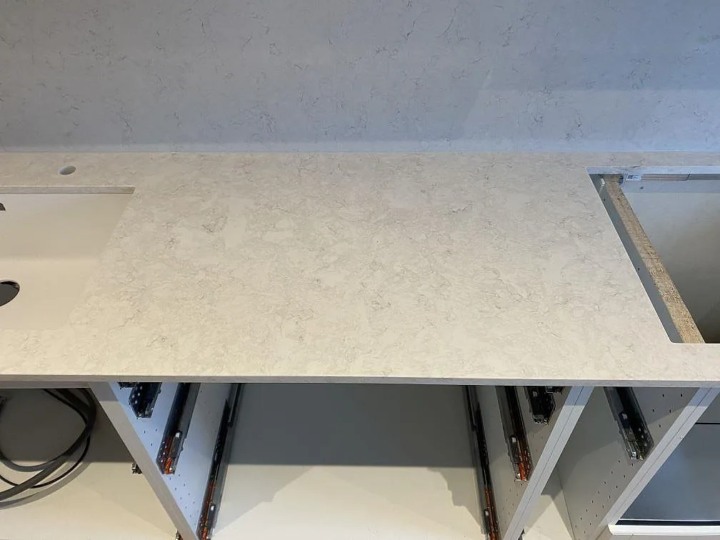 Rak köksbänkskiva i polerad Silestone Snowy Ibiza med förberett öppningsläge i ett kök under montering i Vallberga.