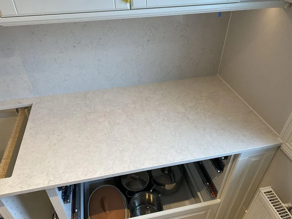 Hörnparti med polerad köksbänkskiva och matchande väggyta i Silestone Snowy Ibiza i ett kök i Vallberga.