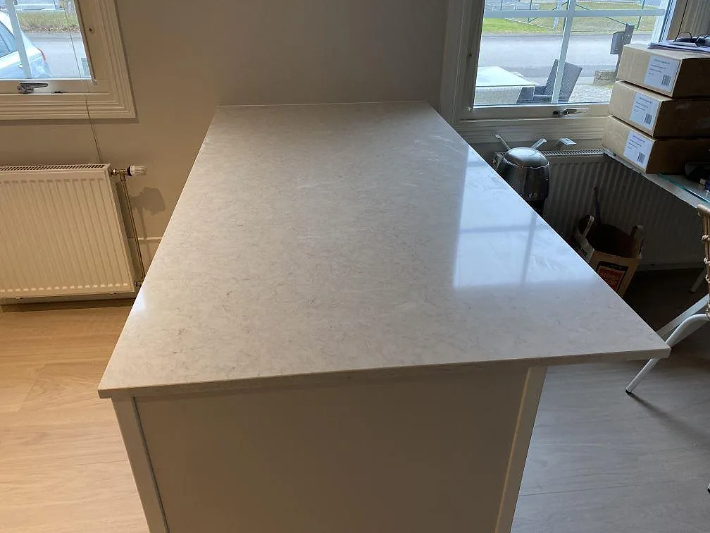 Polerad köksö i Silestone Snowy Ibiza med ljus ådring, monterad som arbetsyta i ett kök i Vallberga.