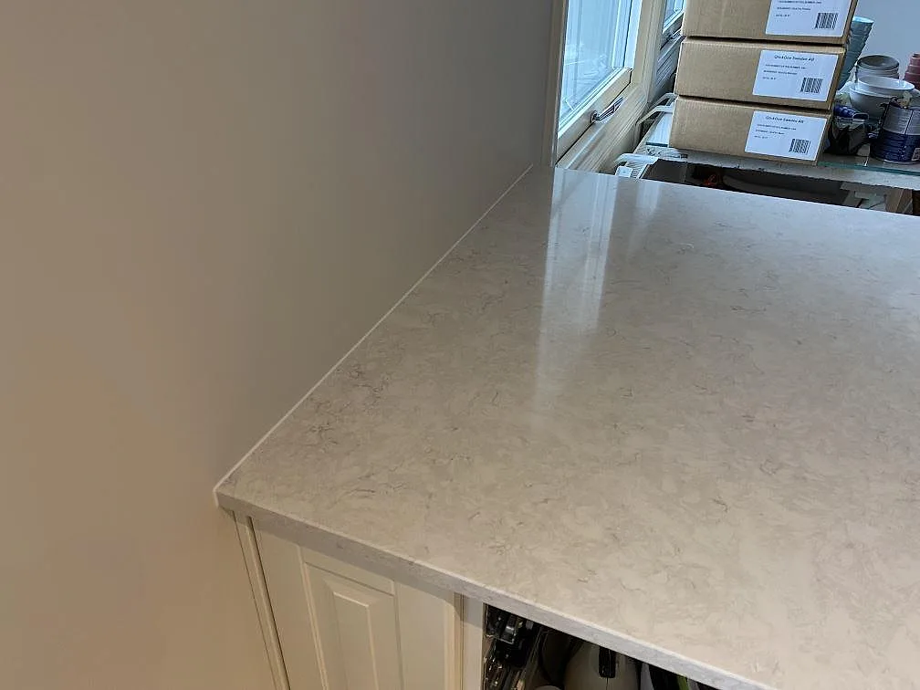 Närbild av polerad Silestone Snowy Ibiza som köksbänkskiva vid fönster, med ljus kvartskomposit och mjuk ådring i Vallberga.