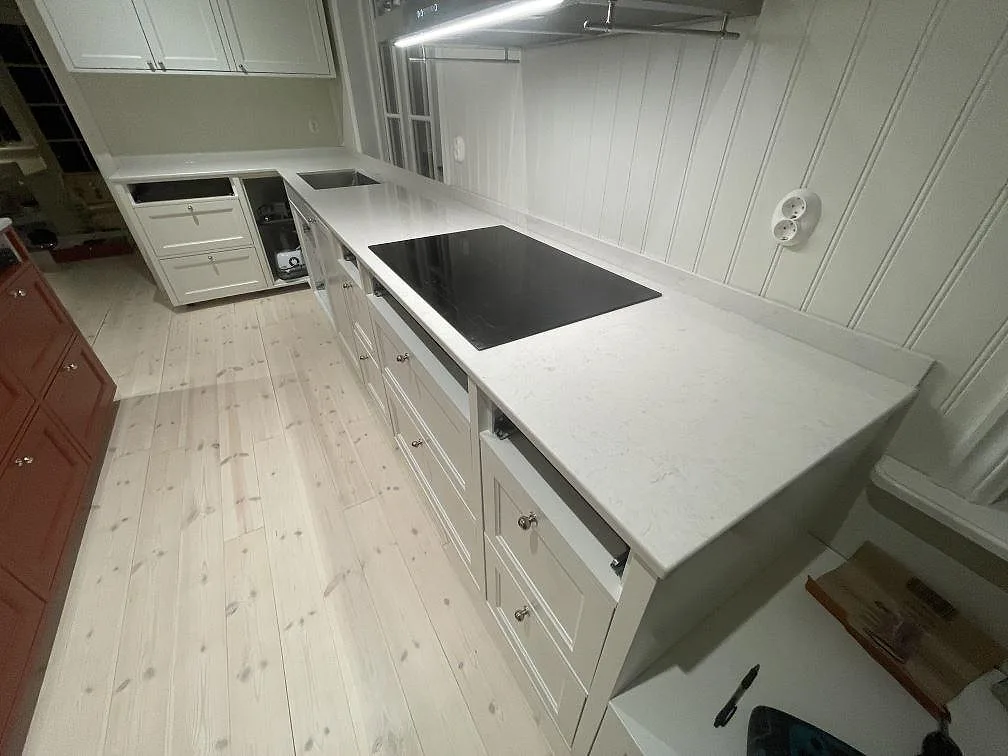Bänkparti i polerad Silestone Snowy Ibiza med infälld induktionshäll och underlimmad rostfri diskho i ett kök i Vallentuna.