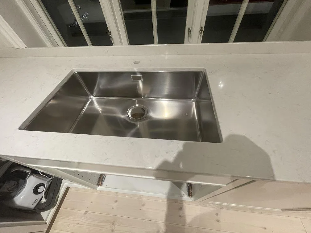 Underlimmad rostfri diskho i polerad Silestone Snowy Ibiza köksbänkskiva sedd uppifrån i ett kök i Vallentuna.