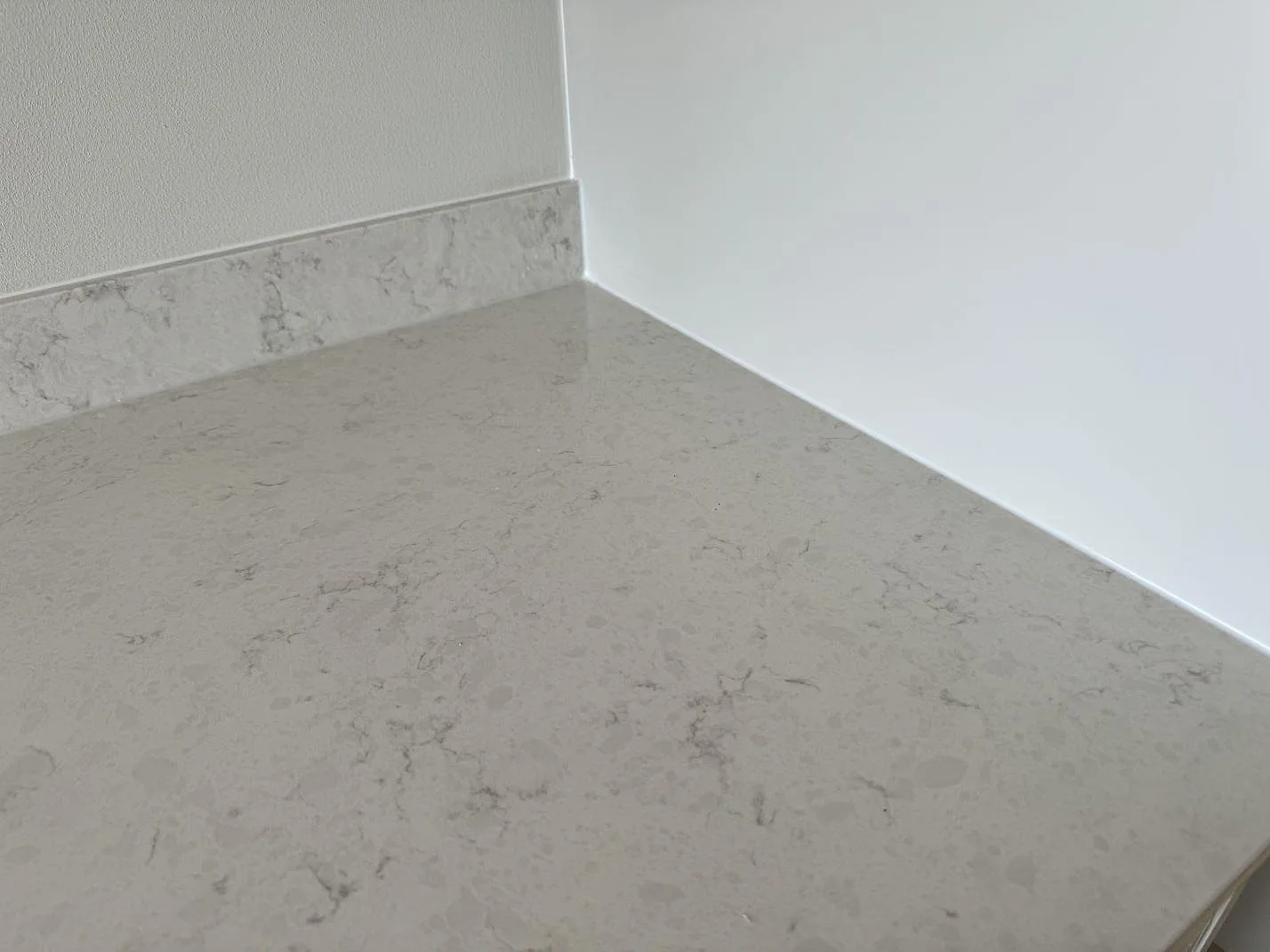 Ytdetalj av polerad Silestone Snowy Ibiza med mjuk grå ådring och uppvikt stänkskydd i Varberg.