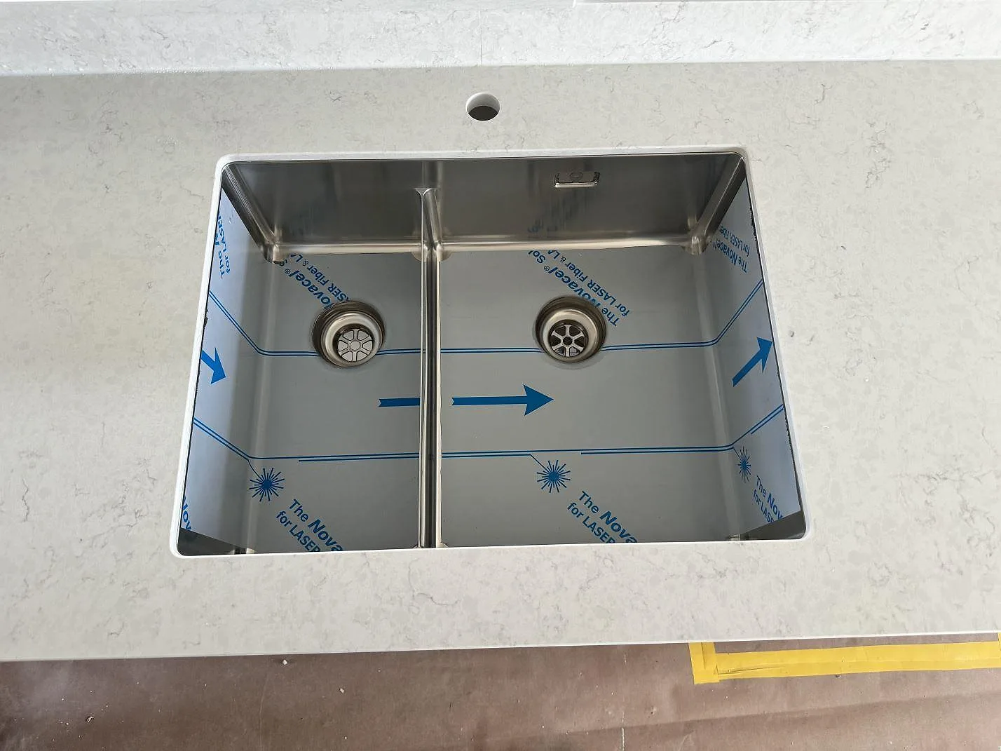 Underlimmad rostfri dubbelho i en polerad kompositbänkskiva av Silestone Snowy Ibiza i ett kök i Varberg.