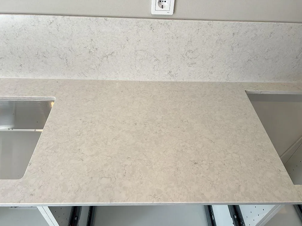 Närbild på polerad Silestone Snowy Ibiza komposit med två urtag, ljus ådring och stänkskydd i köket i Veberöd.
