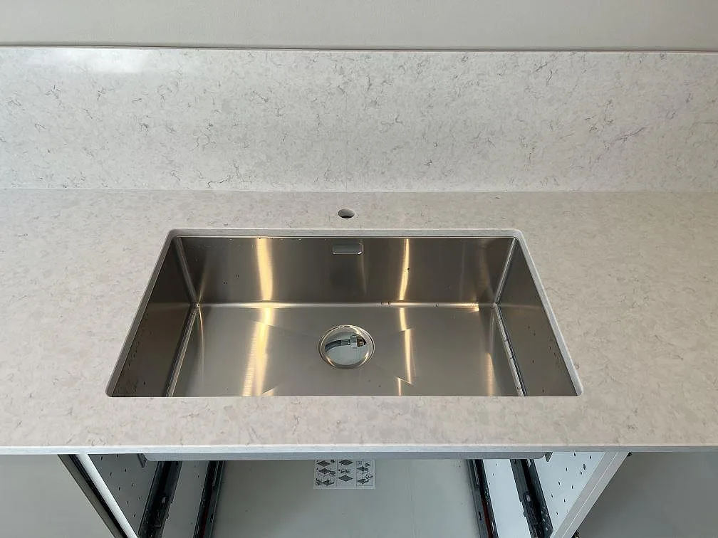 Polerad kompositbänkskiva i Silestone Snowy Ibiza med rektangulär rostfri diskho och stänkskydd i kök i Veberöd.