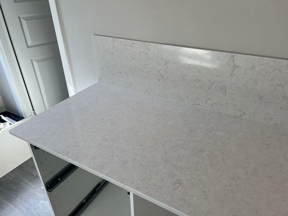 Ljus Silestone Snowy Ibiza komposit som polerad bänkskiva med matchande stänkskydd vid vägg i kök i Veberöd.