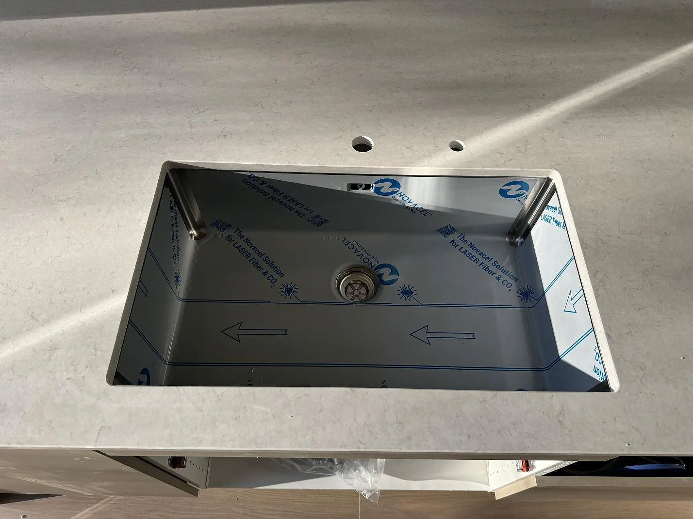 Närbild av underlimmad rostfri diskho i polerad Silestone Snowy Ibiza med blandarhål i Vejbystrand.