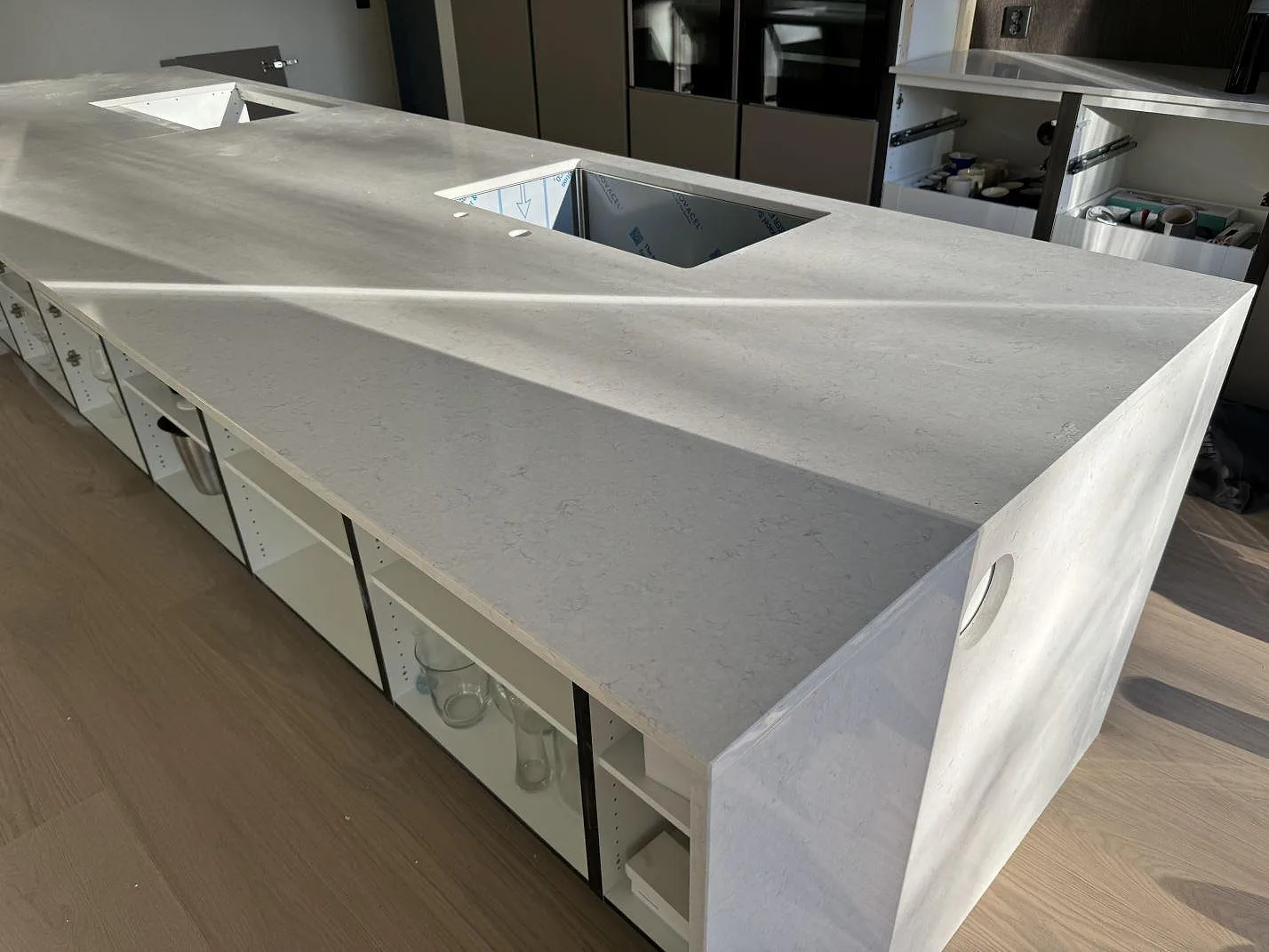 Stor köksö med bänkskiva i polerad Silestone Snowy Ibiza, rostfri diskho och hällurtag i ett kök i Vejbystrand.