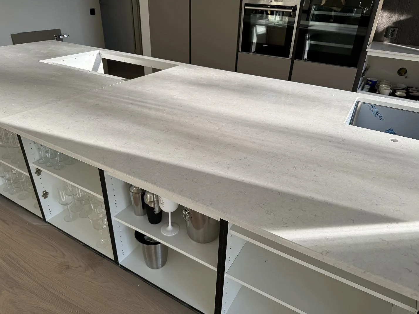 Lång arbetsyta på köksö i polerad Silestone Snowy Ibiza med diskho och hällöppning i Vejbystrand.