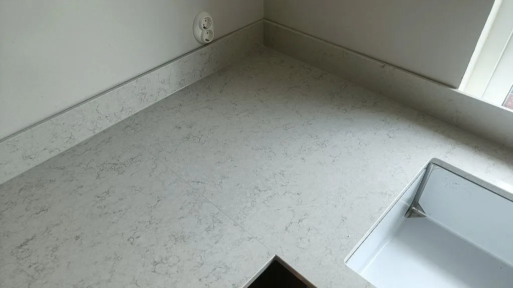 Köksbänkskiva i Silestone Snowy Ibiza med underlimmad diskho och låg uppvikt stänkkant i ett kök i Vellinge.