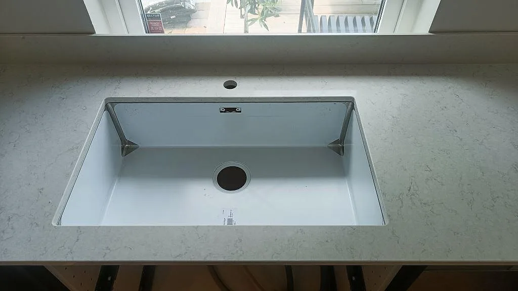 Stor underlimmad diskho i en köksbänkskiva av vit Silestone Snowy Ibiza vid fönstret i ett kök i Vellinge.
