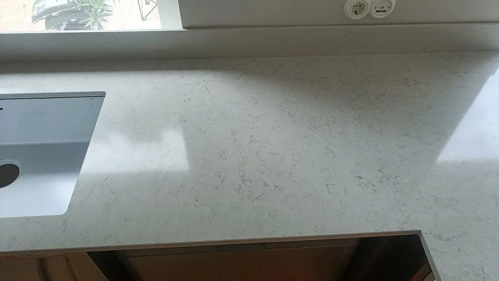 Bänkskiva i polerad Silestone Snowy Ibiza med underlimmad diskho och eluttag i ett kök i Vellinge.
