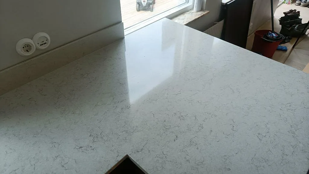 Polerad köksbänkskiva i Silestone Snowy Ibiza som speglar fönsterljuset i ett kök i Vellinge.