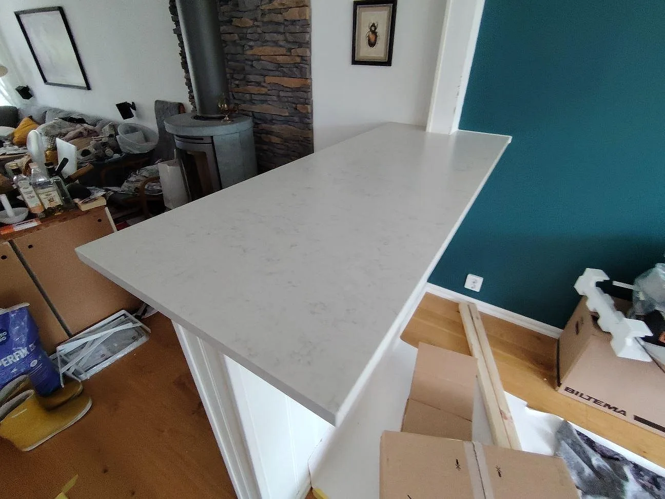 Anslutande bänkdel i Silestone Snowy Ibiza, matt Mocka, vid blågrön accentvägg och synligt tegel i Vendelsö.