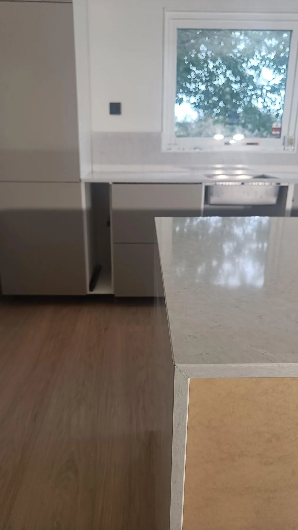 Vertikal detaljbild av polerad Silestone Snowy Ibiza på köksön, med bakre bänkrad och lågt stänkskydd i köket i Viken.