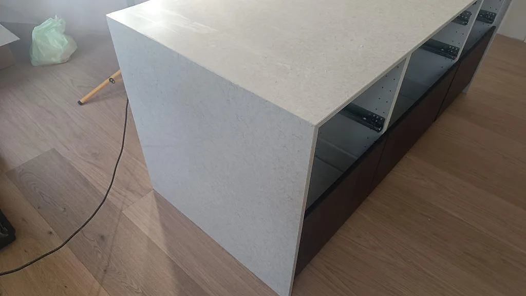 Närbild på stenklädd gavel i Silestone Snowy Ibiza, polerad ljus kvartskomposit på köksön i Viken.