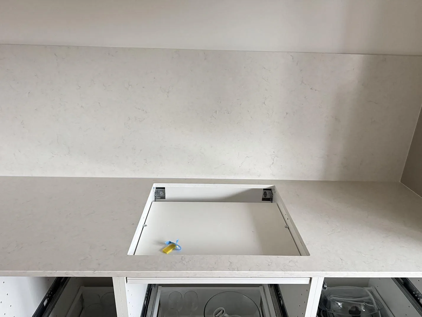 Förberett hällurtag i en vit polerad Silestone Snowy Ibiza-bänkskiva med matchande stänkskydd i ett kök i Ystad.