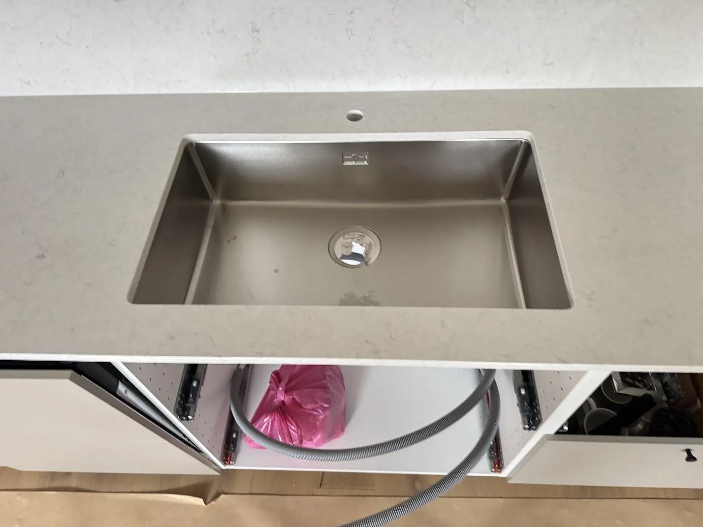 Närbild på underlimmad rostfri diskho i en vit Silestone Snowy Ibiza-köksbänkskiva med polerad yta i Ystad.