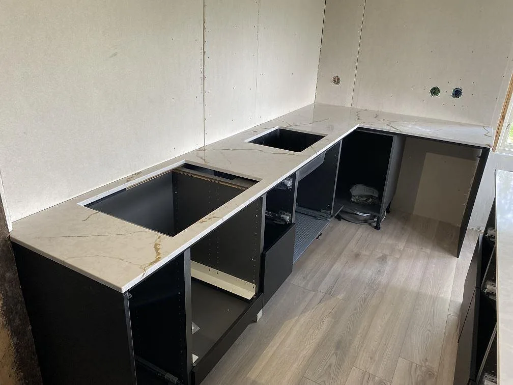 L-formad köksbänkskiva i polerad Silestone Versallies Ivory med hälluttag och svart diskho i Varberg.