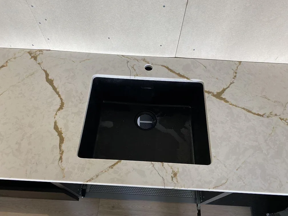 Svart diskho monterad i polerad Silestone Versallies Ivory med varm ådring i ett kök i Varberg.