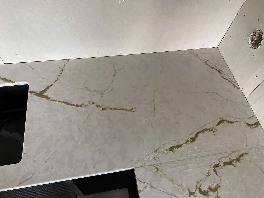 Närbild på polerad Silestone Versallies Ivory vid kökets hörn med gyllene ådring i Varberg.