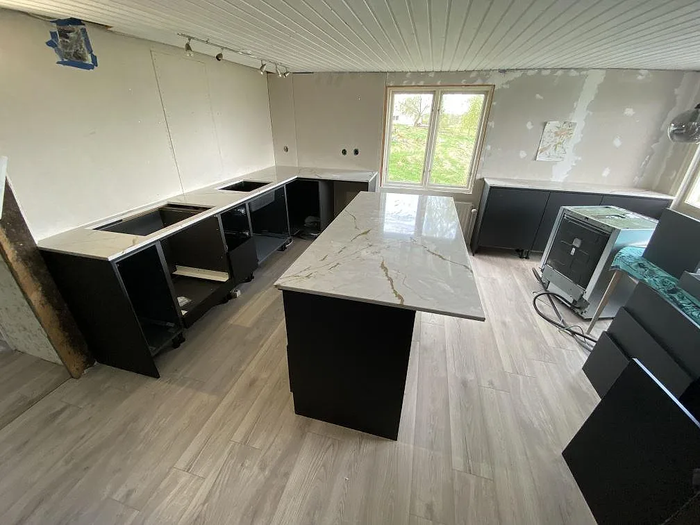 Köksbänkskiva och köksö i polerad Silestone Versallies Ivory med ljus ådring i ett kök under montering i Varberg.