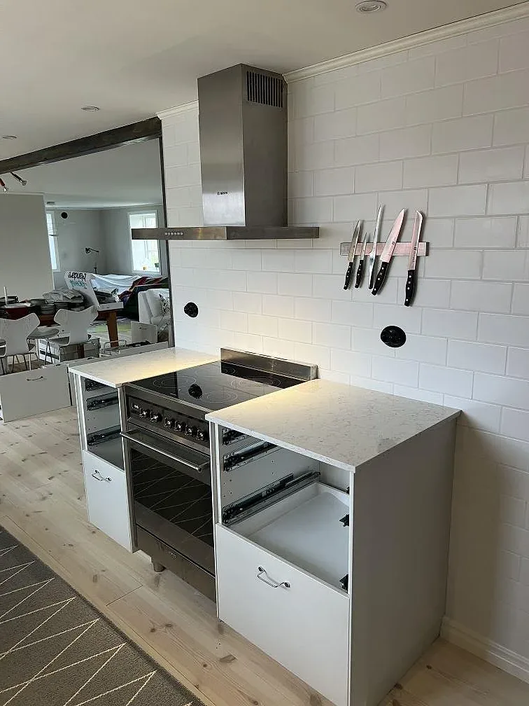 Köksbänkskiva i polerad Silestone White Arabesque, 20 mm kvartskomposit, vid fristående spis och vita skåp i Villands Vånga.