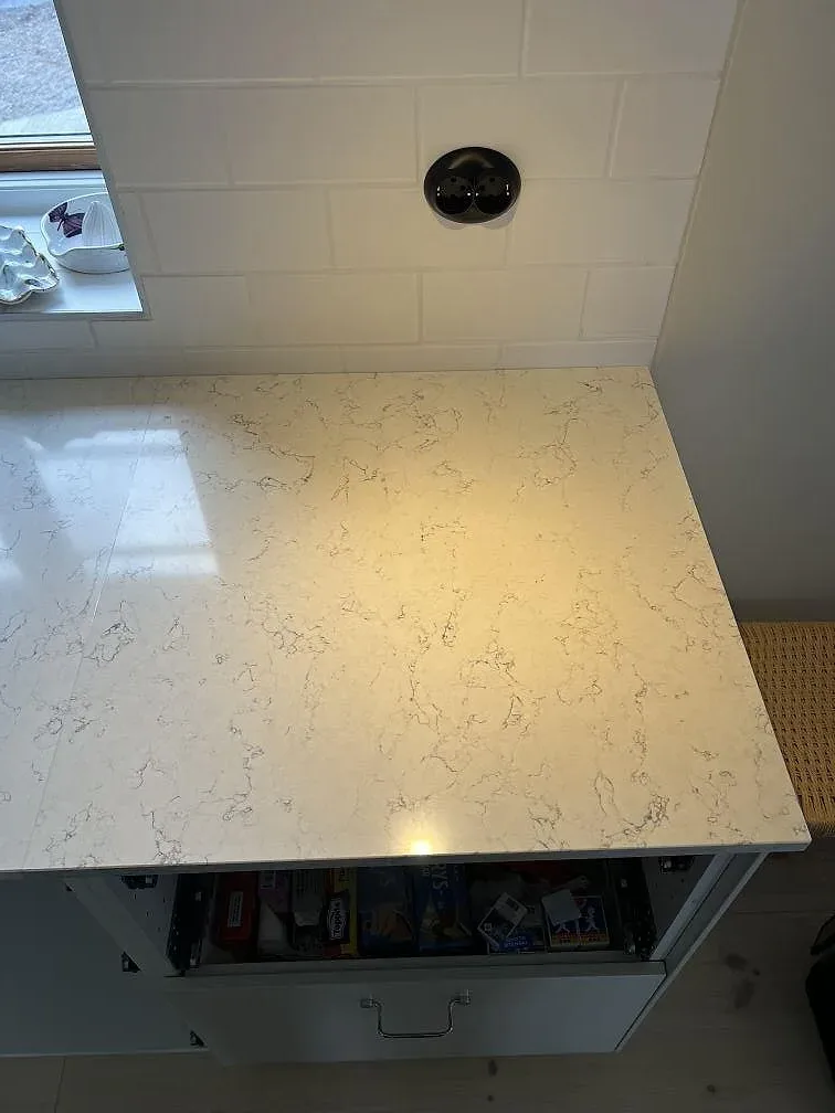 Närbild på polerad Silestone White Arabesque som ljus kvartskompositbänkskiva med grå ådring i köket i Villands Vånga.