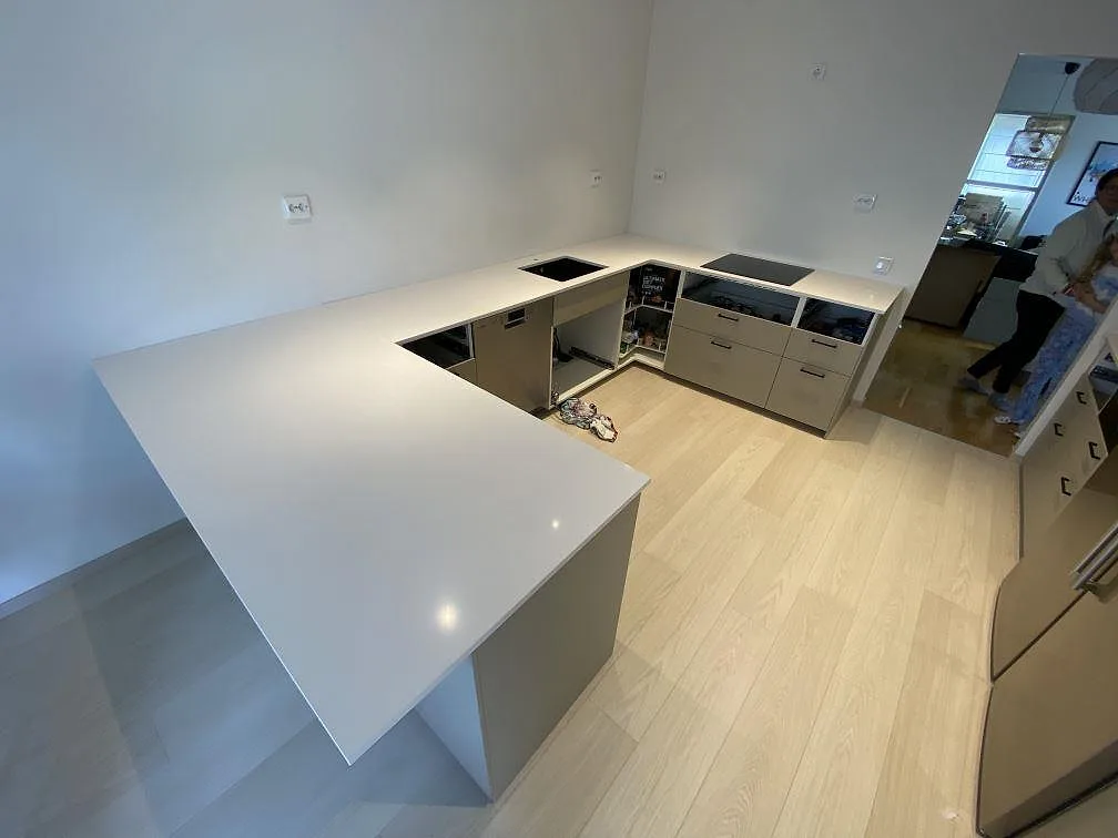Köksbänkskiva i vit Silestone White Storm, polerad kvartskomposit, U-format kök med urtag för diskho och induktionshäll i Helsingborg.
