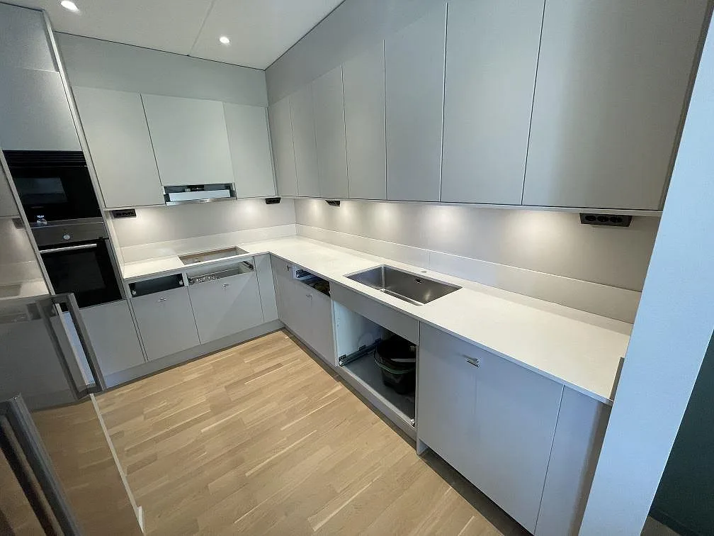 Polerad vit Silestone Yukon i kvartskomposit som köksbänkskiva i ett L-format kök i Örebro, med diskho, hällurtag och stänkskydd.