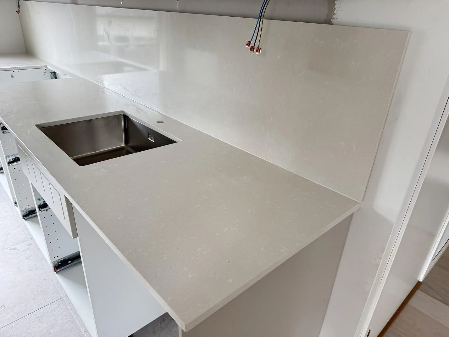 Köksbänkskiva i polerad Silestone Yukon komposit med rostfri diskho och matchande väggbeklädnad i ett kök i Råå.