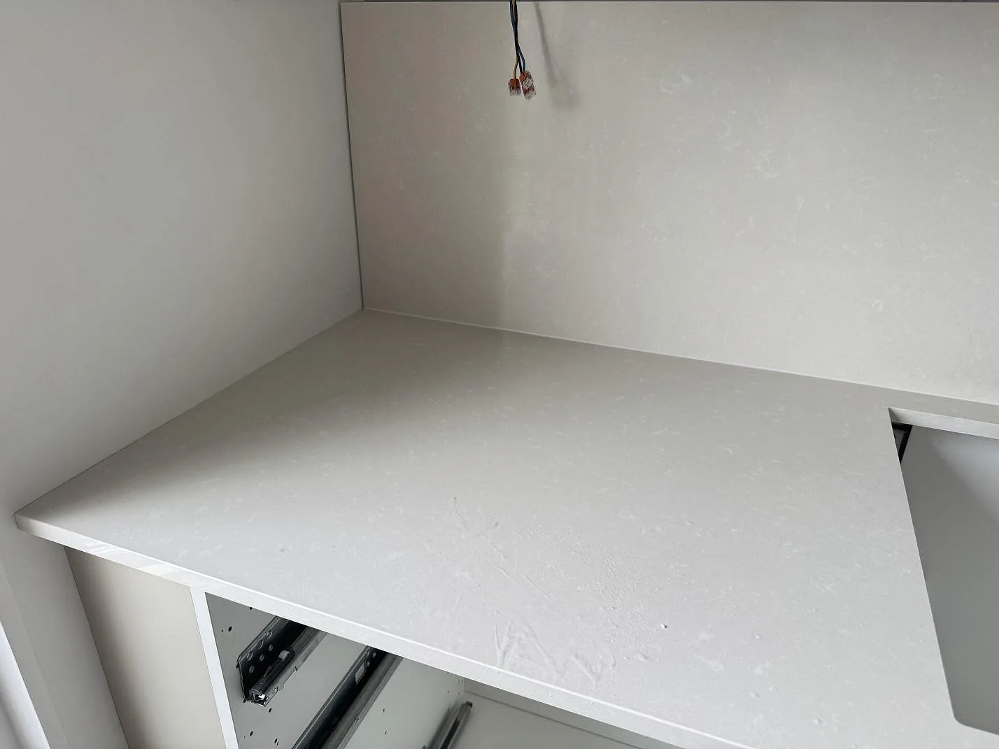 Polerad Silestone Yukon köksbänkskiva med ljus väggbeklädnad och öppna köksstommar under montering i Råå.