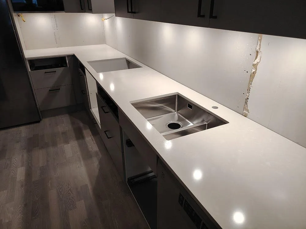 Närbild av polerad Silestone Yukon som köksbänkskiva med rostfri diskho och hällöppning i ett kök i Västerås.