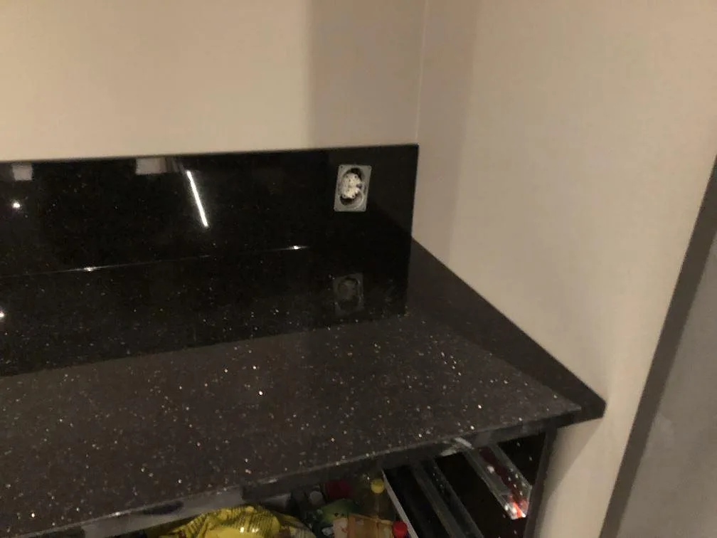 Hörn med bänkskiva och uppvikt stänkkant i svart Star Galaxy granit med eluttag, i ett kök i Alingsås.