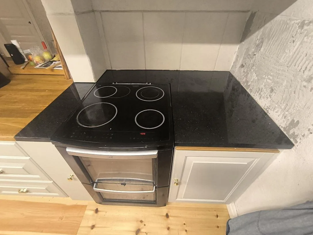 Köksbänkskiva i svart Star Galaxy granit, polerad, monterad runt spis i ett kök i Grangärde.
