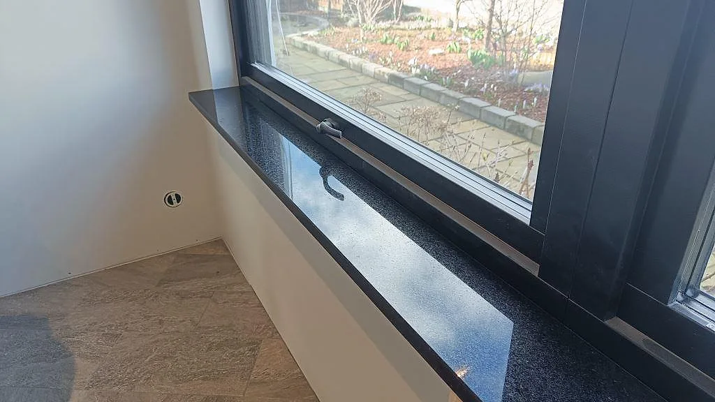 Närbild på blank fönsterbänk i Star Galaxy granit med svart fönsterparti i Löddeköpinge.