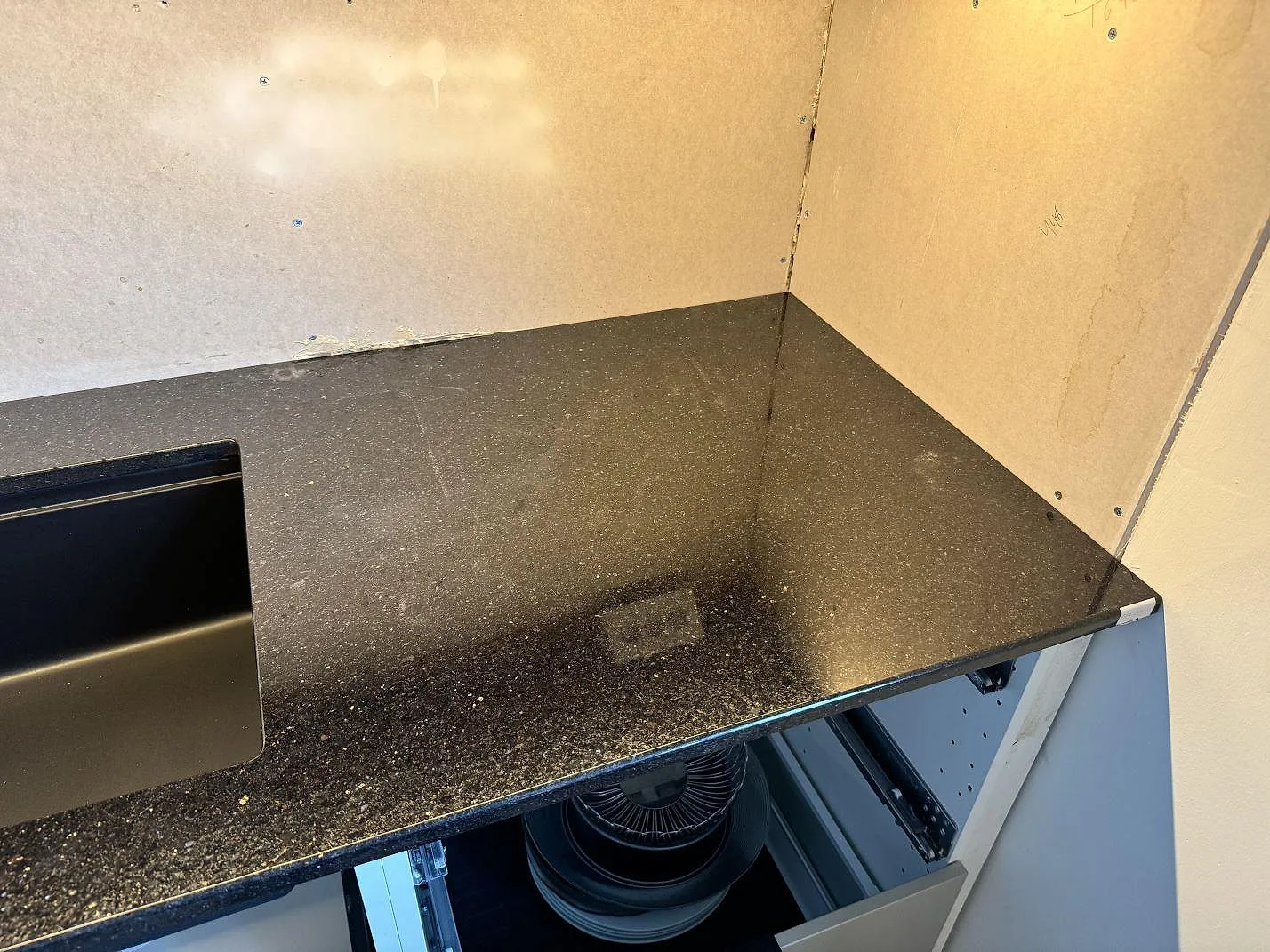 Köksbänkskiva i polerad Star Galaxy granit med svart underlimmad diskho och öppna stommar under montering i Malmö.