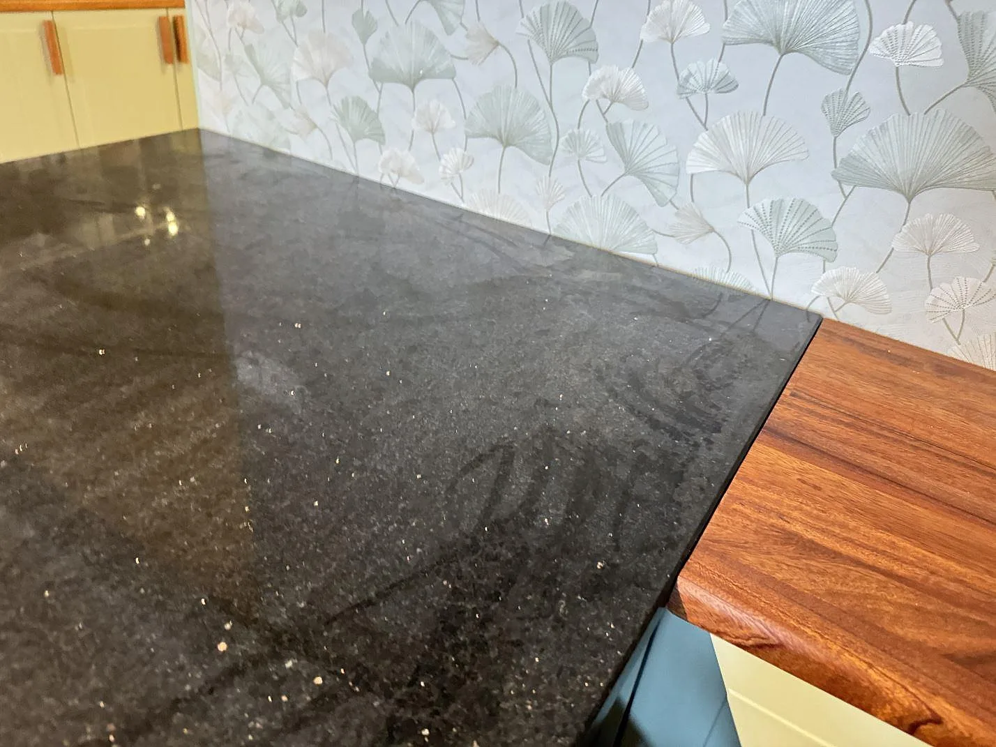 Detalj av polerad Star Galaxy granit mot träyta och mönstrad vägg i köket i Marieholm.
