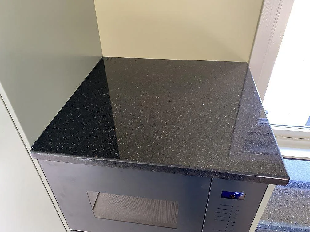 Detalj av polerad Star Galaxy-granit med glittrande korn på en mindre arbetsyta i köket i Mellbystrand.