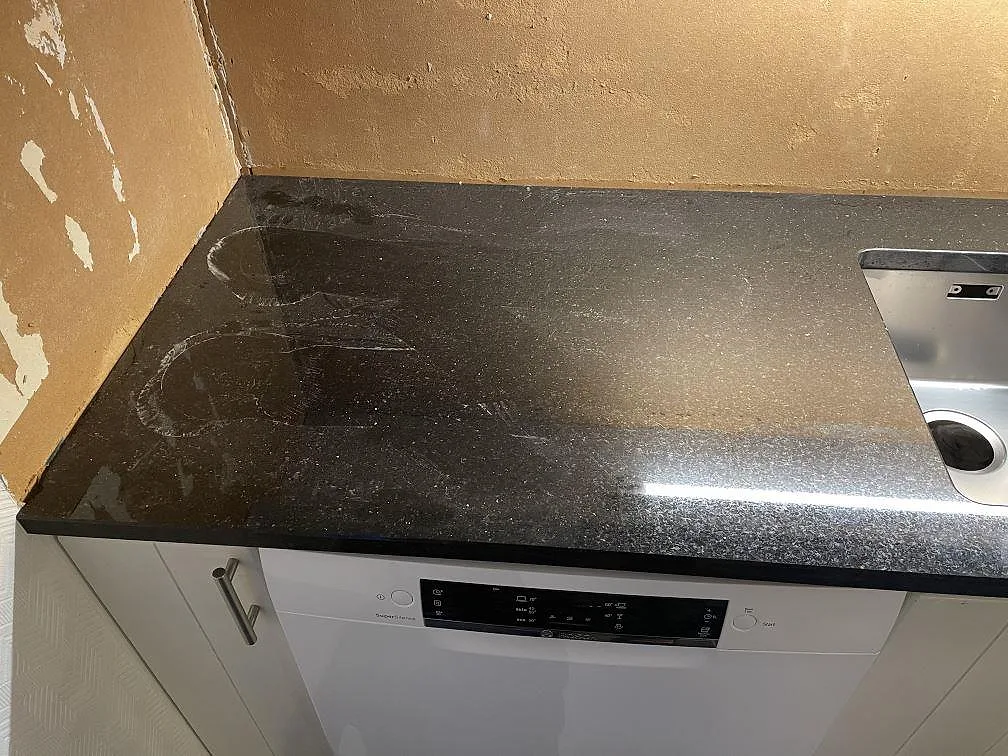 Köksbänkskiva i polerad svart Star Galaxy granit med plats för diskmaskin i ett kök under inredning i Ödsmål.
