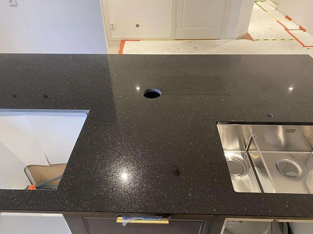 Polerad Star Galaxy-granit över köksön med diskho, hällöppning och synliga guldtonade korn i Trelleborg.