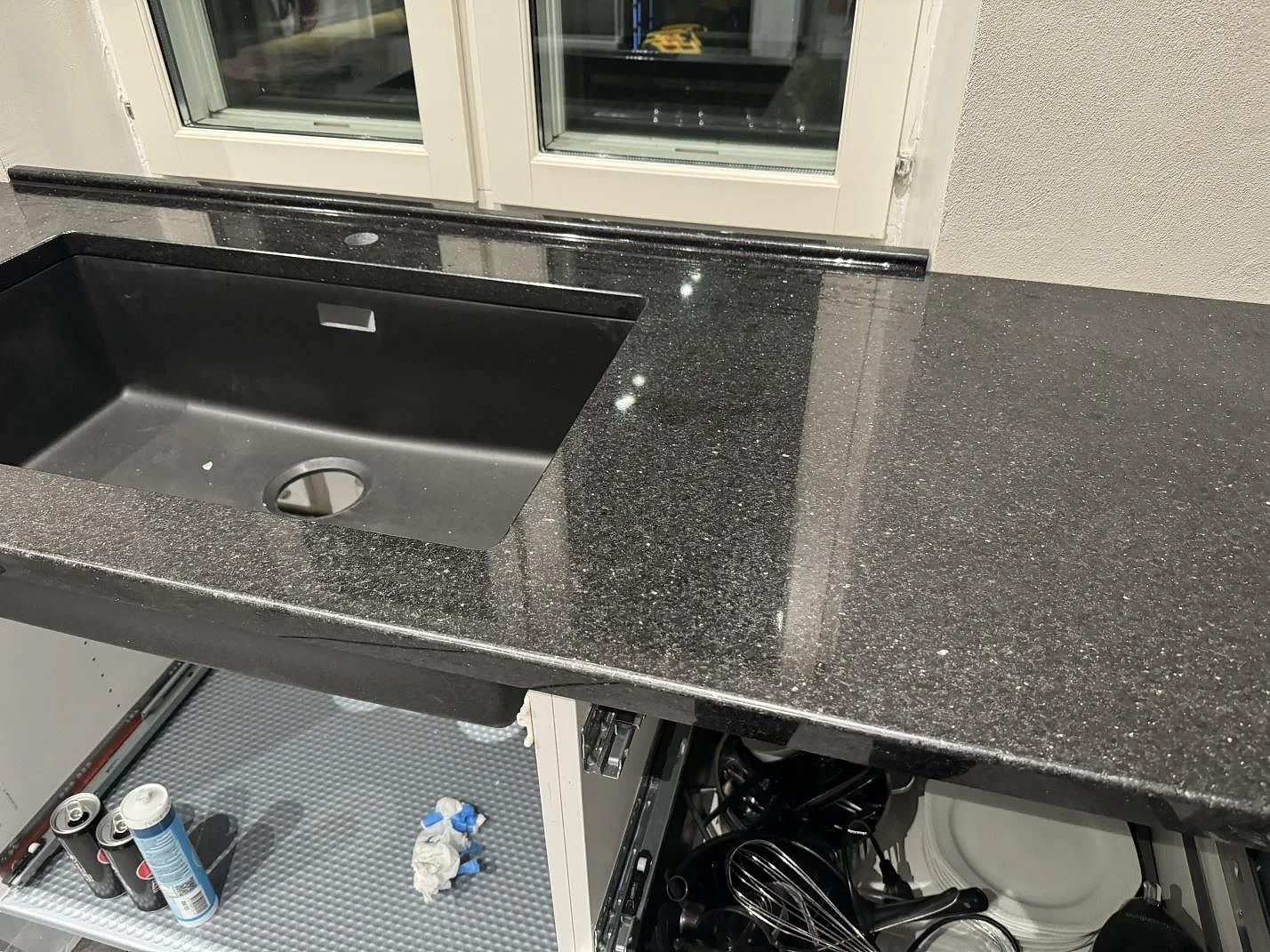 Köksbänkskiva i polerad Star Galaxy granit med underlimmad diskho och fönsterkant i ett kök i Trelleborg.