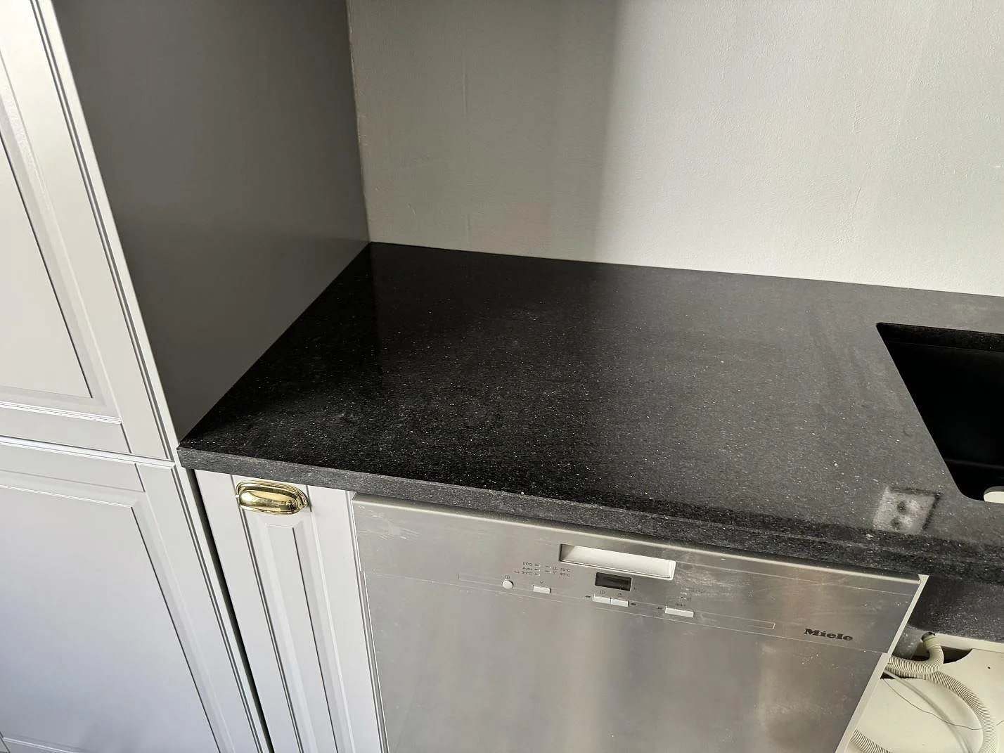 Polerad Star Galaxy granit över diskmaskin med svart diskho och grå köksinredning i Vinslöv.