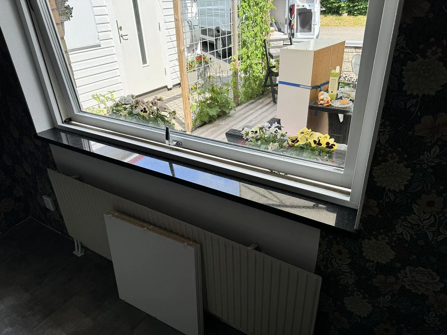 Fönsterbänk i polerad Star Galaxy granit vid floral tapet och köksfönster i Vinslöv.