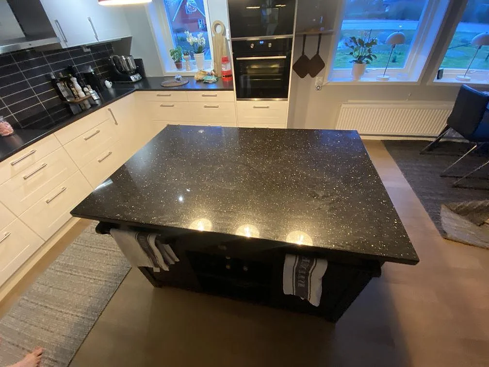 Köksö med bänkskiva i Star Gate, polerad grå-brun granit med gnistrande korn, 30 mm, i ett kök i Löberöd.
